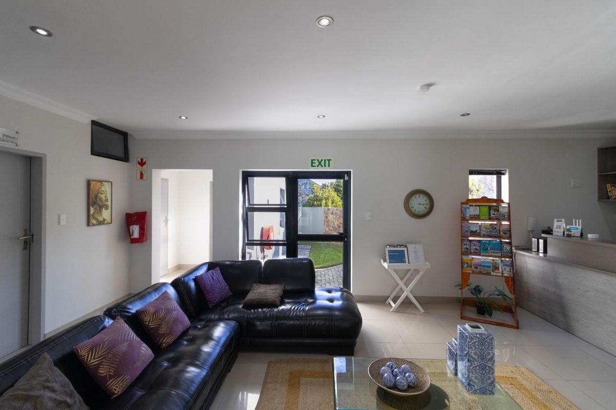 A bright and well-maintained living area featuring tiled flooring, recessed downlighting, and direct access to the exterior through a glass door.