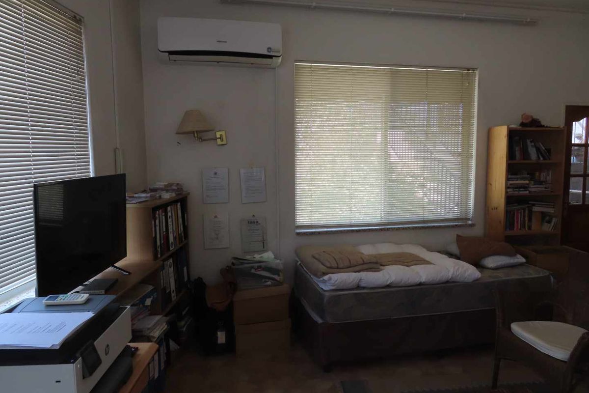 A bedroom featuring a wall-mounted air conditioning unit, venetian blinds, and tiled flooring.