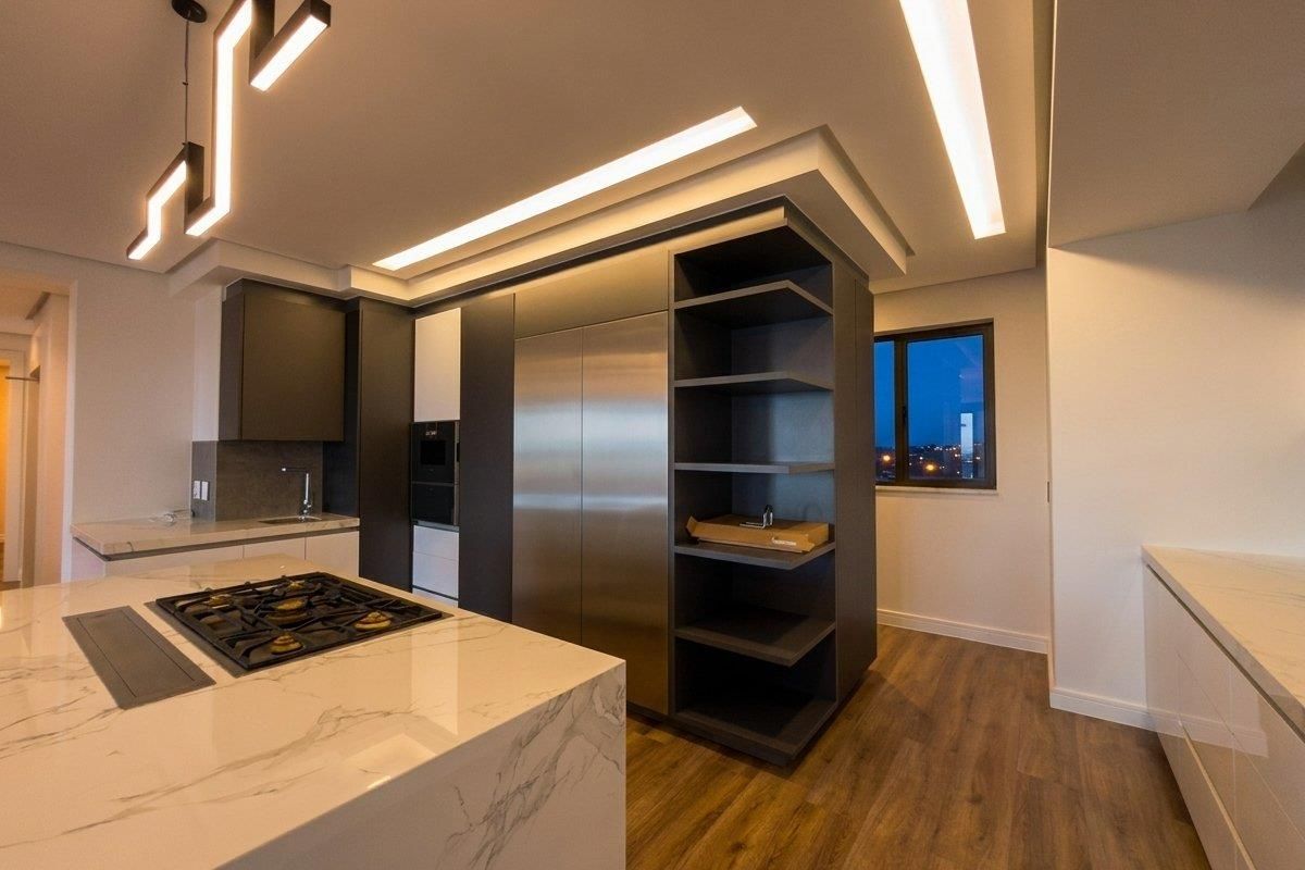 Modern kitchen featuring a marble-topped island with integrated gas hob, sleek dark cabinetry, built-in appliances, and recessed ceiling lighting.