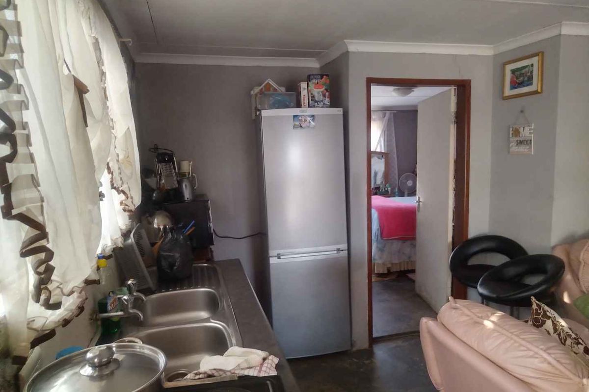 A compact kitchen area featuring a double bowl stainless steel sink and countertop, showing signs of wear and requiring maintenance.