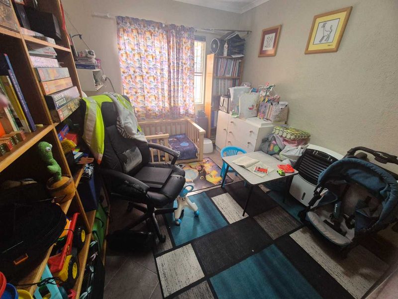 A bedroom featuring tiled flooring and a window with a curtain rod, currently utilized as a multi-purpose hobby and storage space.