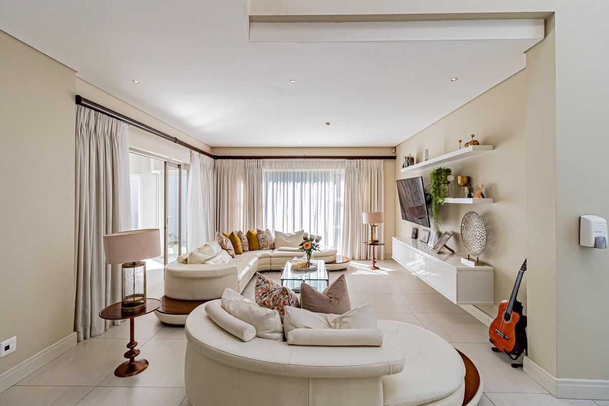 Spacious living room featuring large format floor tiles, recessed ceiling lighting, and built-in wall-mounted cabinetry with floating shelving.