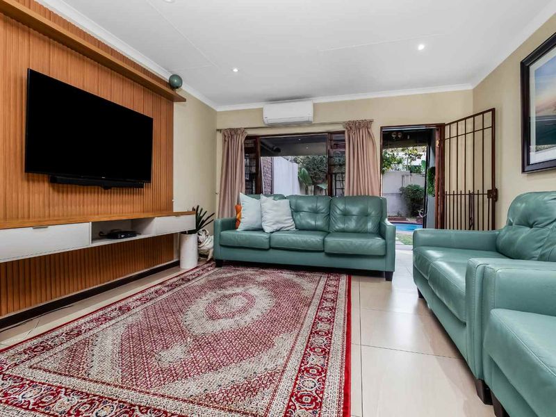 A comfortable living room featuring a custom built-in media unit, tiled flooring, and direct access to the outdoor patio area.