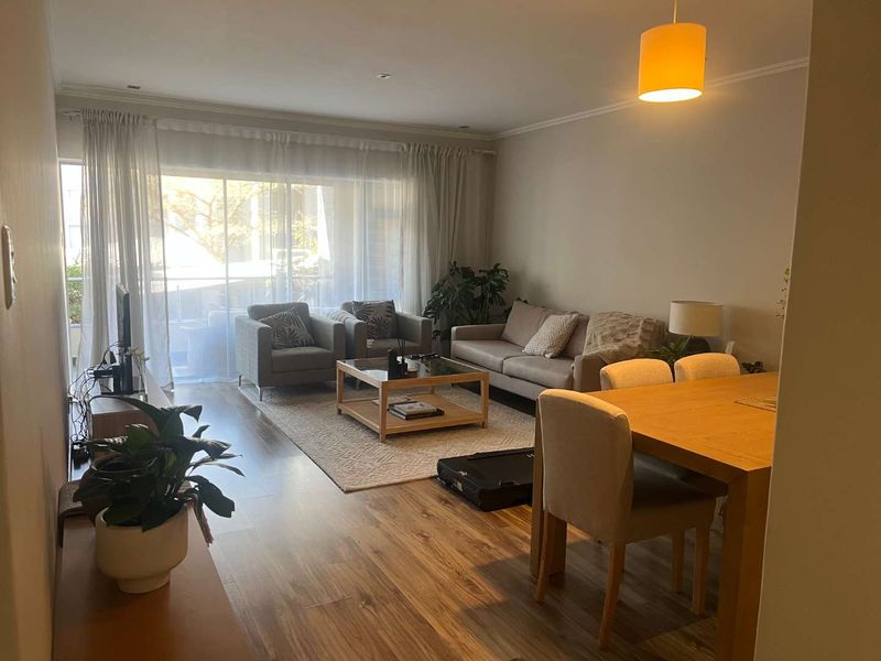 Spacious open-plan living and dining area featuring laminate flooring, neutral walls, and large sliding glass doors leading to a balcony.