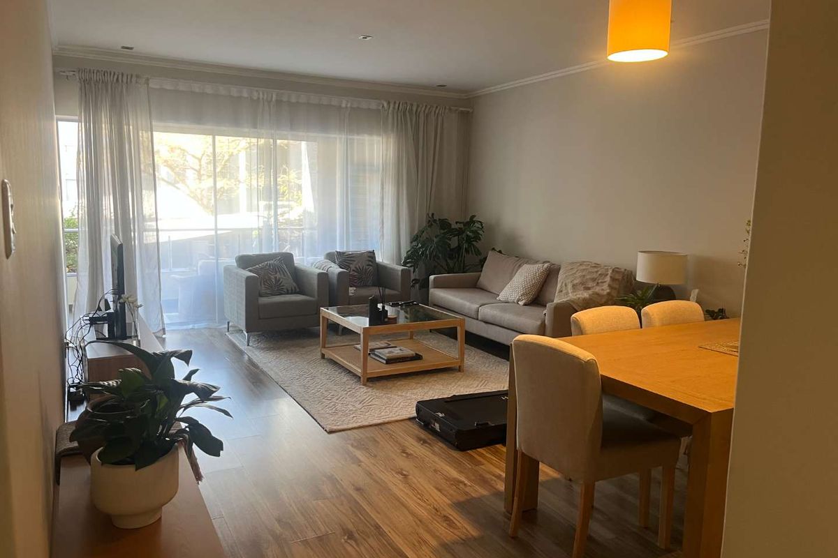 Spacious open-plan living and dining area featuring laminate flooring, neutral walls, and large sliding glass doors leading to a balcony.