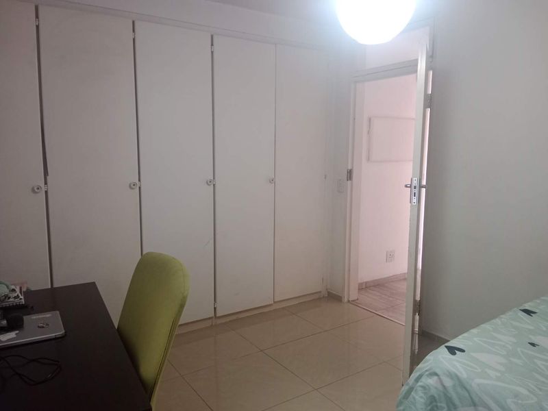 A bedroom featuring built-in cupboards and tiled flooring, providing a functional space with direct access to an adjacent room.