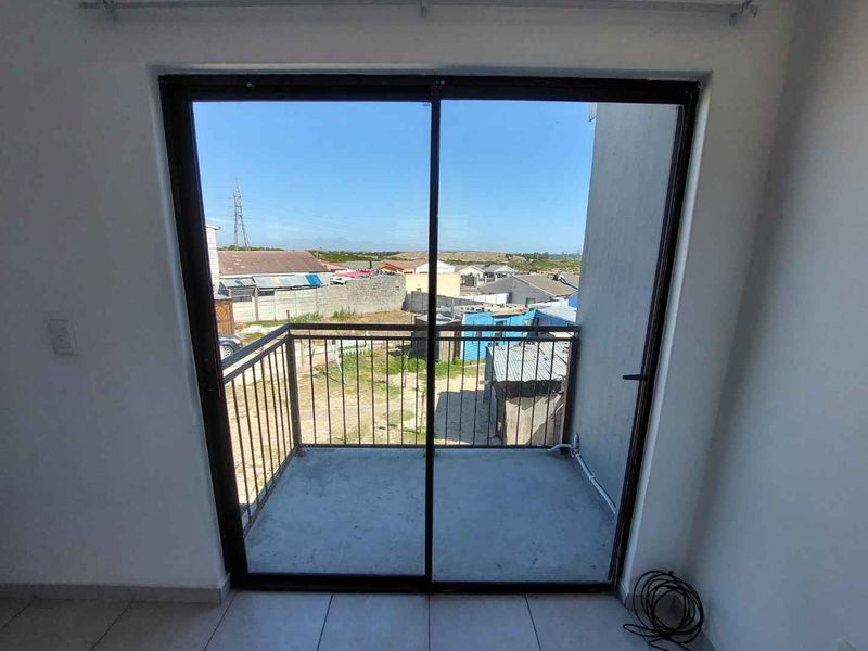 A compact balcony featuring a metal balustrade and sliding glass door access, offering an elevated view of the surrounding neighborhood.