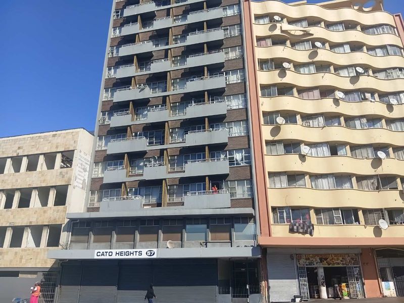 Exterior view of the Cato Heights apartment building featuring a multi-story brick facade with individual balconies and ground-level commercial security shutters.
