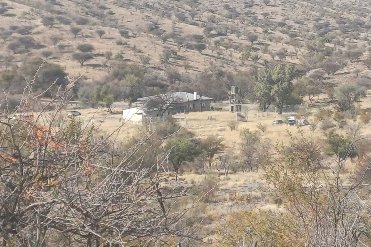 An elevated view of a rural farm property featuring a main dwelling, water storage infrastructure, and surrounding natural landscape.