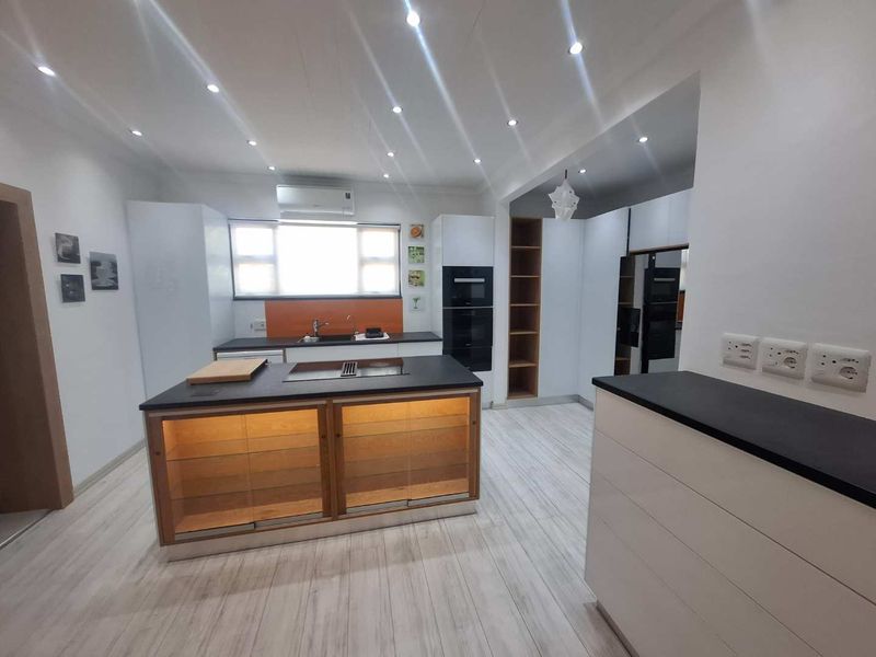 Modern kitchen featuring a central island with integrated storage, built-in appliances, sleek cabinetry, and recessed lighting throughout.