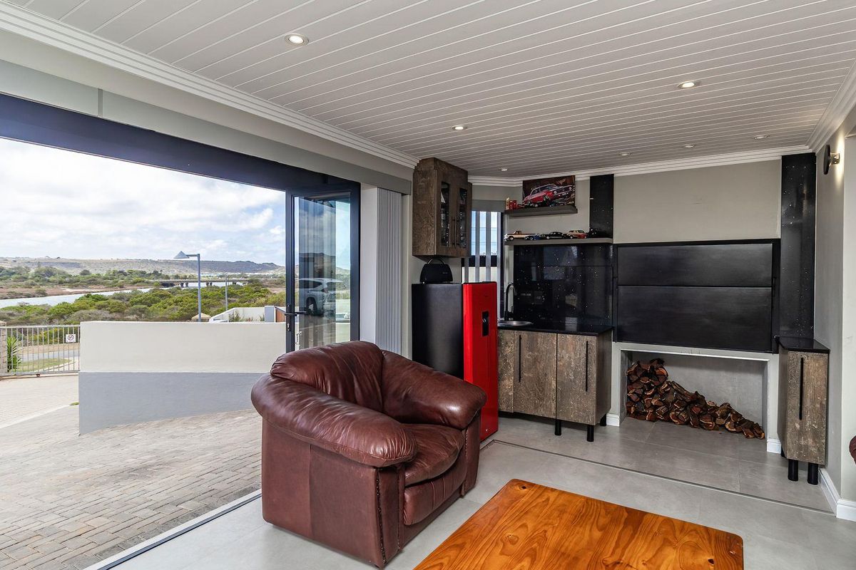 Indoor entertainment area featuring a built-in braai, kitchenette, and large sliding doors opening to a scenic outdoor view.