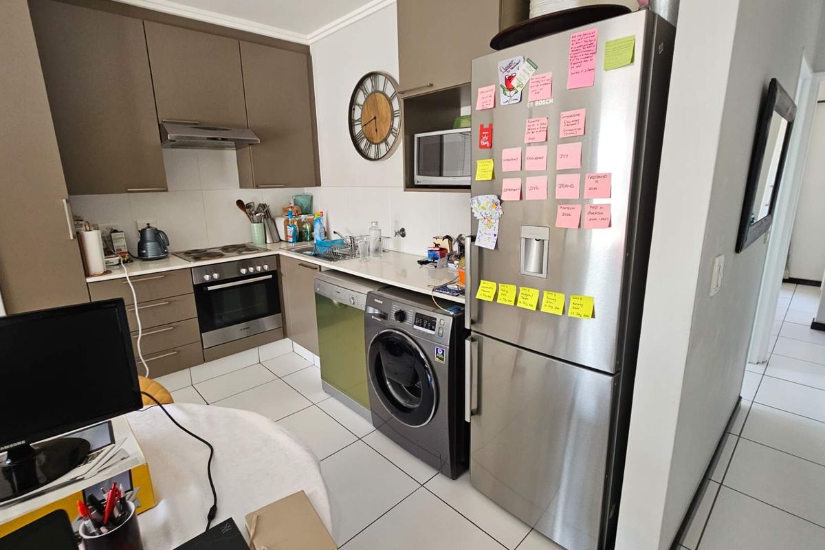 Functional kitchen featuring modern cabinetry, built-in oven, hob, extractor fan, and integrated appliances with tiled flooring throughout.
