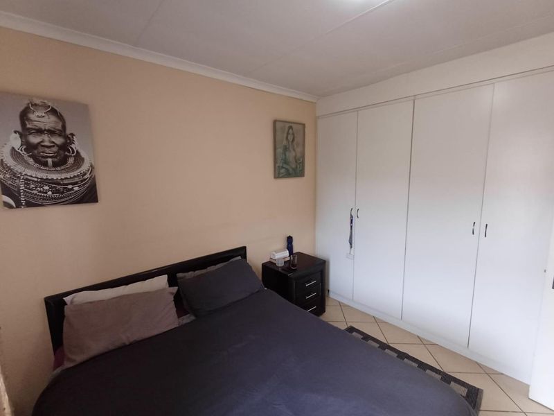 A bedroom featuring built-in cupboards, tiled flooring, and a coved ceiling, providing a functional and neutral living space.