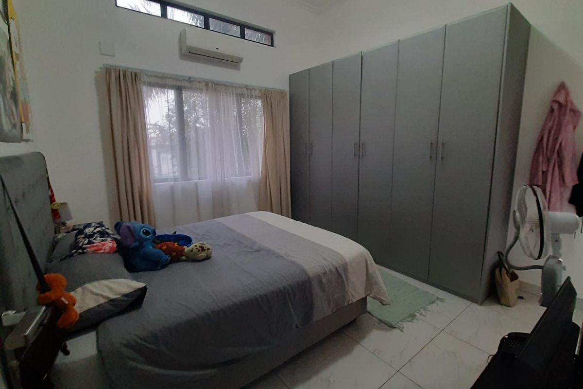 A well-lit bedroom featuring extensive built-in cupboards, tiled flooring, and a wall-mounted air conditioning unit.