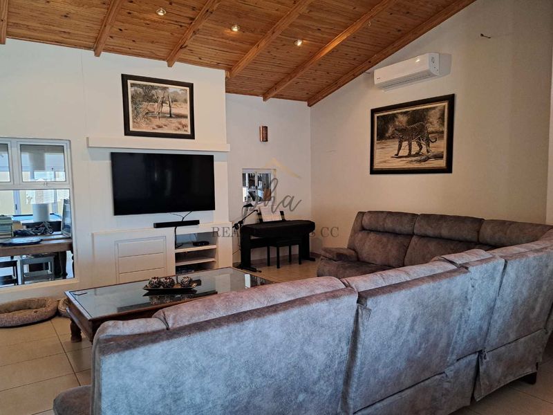 Spacious living room featuring a high exposed timber beam ceiling, tiled flooring, and a built-in media console with integrated air conditioning.