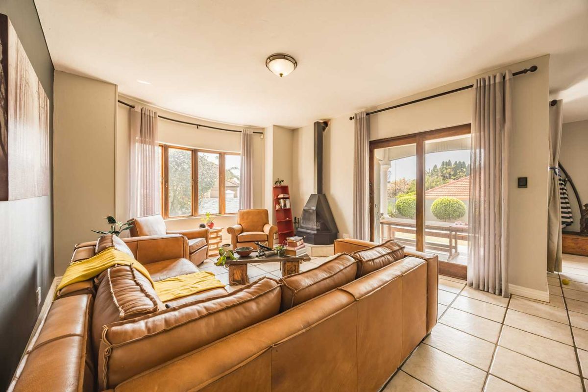 Spacious living room featuring tiled flooring, a freestanding fireplace, and large windows with sliding door access to the outdoor patio area.