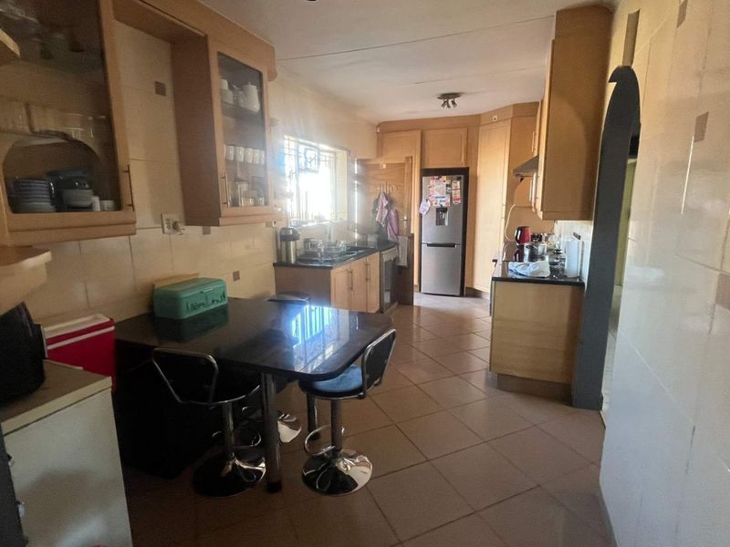 A functional kitchen featuring built-in wooden cabinetry, tiled flooring, and a tiled backsplash, offering a practical layout with ample storage space.