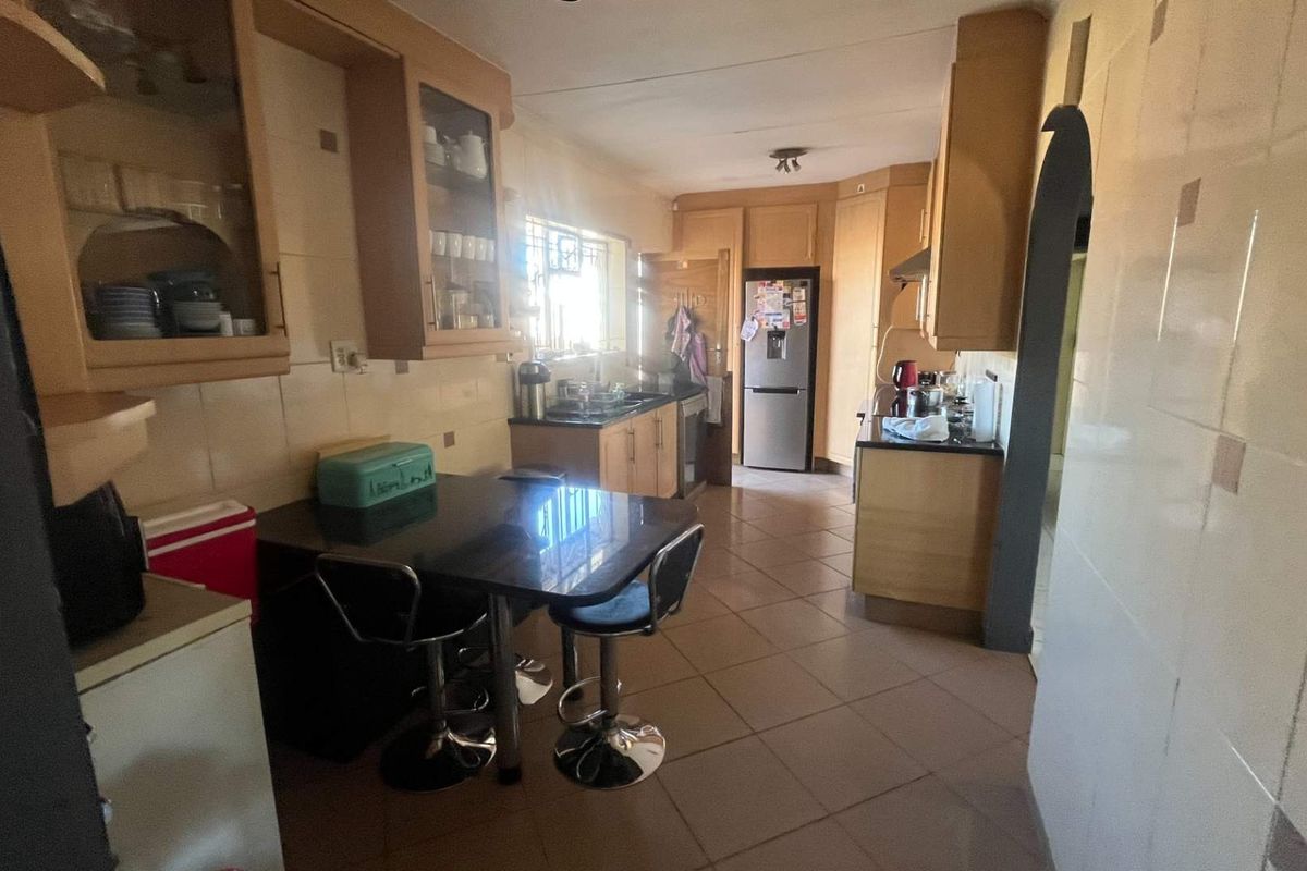 A functional kitchen featuring built-in wooden cabinetry, tiled flooring, and a tiled backsplash, offering a practical layout with ample storage space.