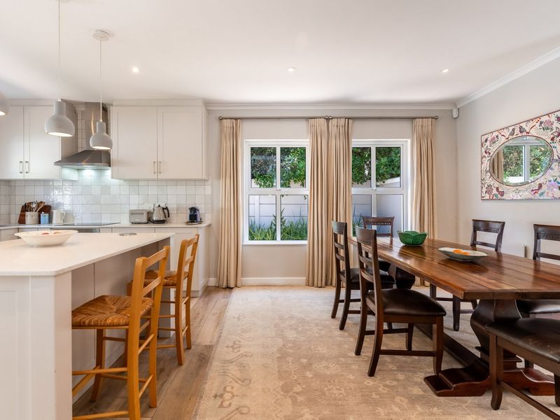 A bright open-plan kitchen and dining area featuring a central island, modern cabinetry, tiled backsplash, and neutral finishes throughout.