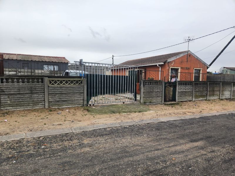 Front view of a detached house featuring a tiled roof, metal security gate, and a precast concrete boundary wall.