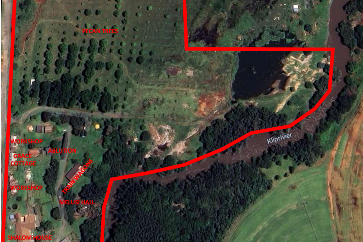 Aerial view of a large farm property featuring pecan trees, river frontage, and various residential and workshop structures.