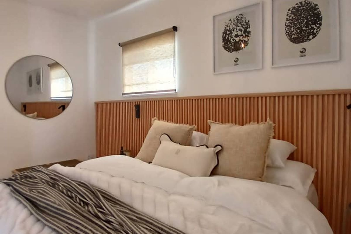 A well-appointed bedroom featuring a modern timber slat headboard, neutral decor, and a contemporary pendant light fixture.