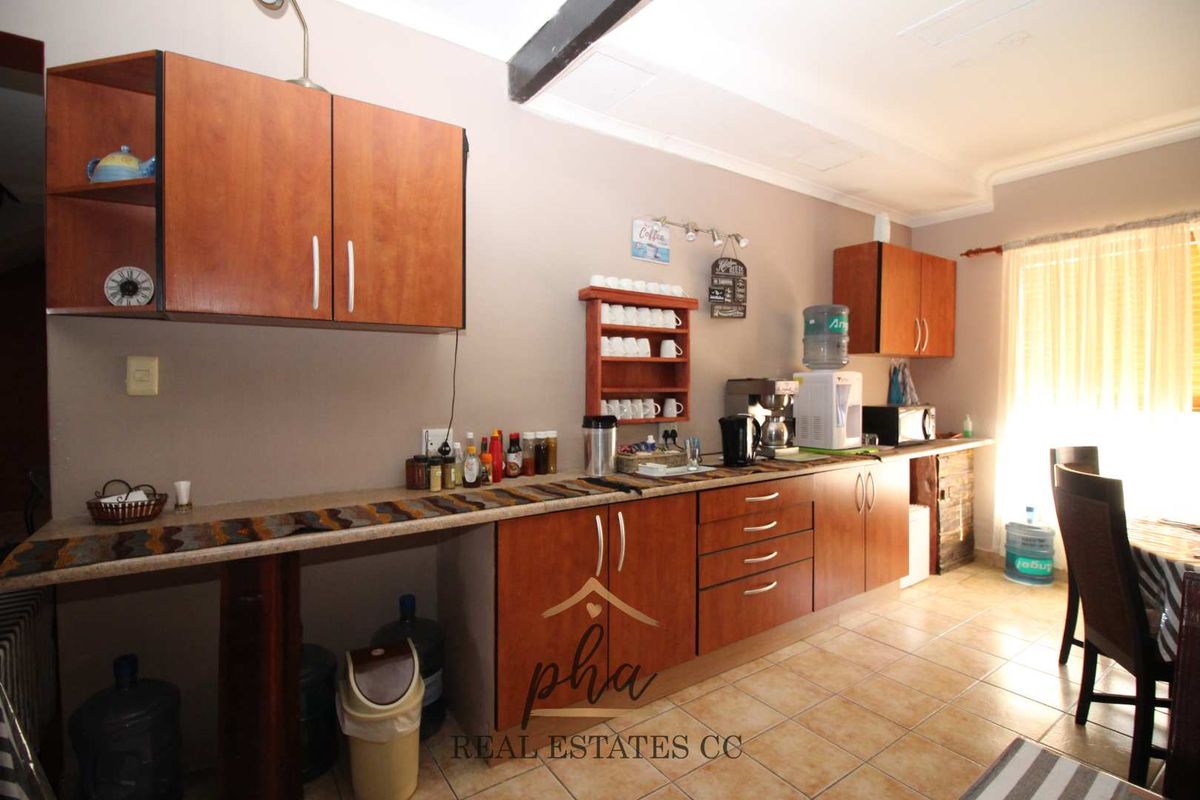A functional kitchen area featuring wood-finish cabinetry, tiled flooring, and ample counter space for food preparation and storage.
