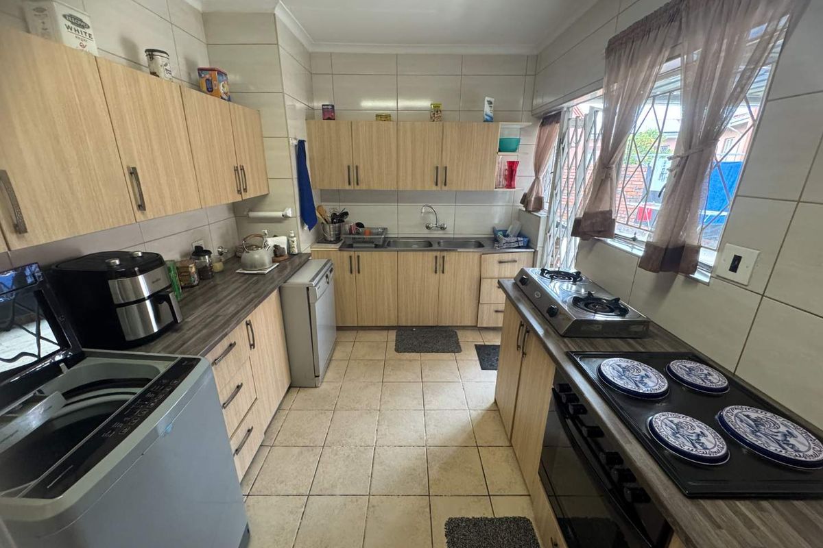 Functional kitchen featuring light wood-finish cabinetry, laminate countertops, tiled splashbacks, and a built-in oven with a gas hob.