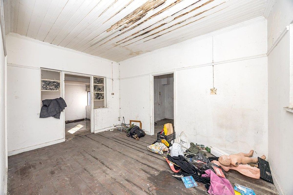 A vacant room featuring original timber flooring and a damaged ceiling, requiring significant renovation and repair to restore its structural integrity and aesthetic appeal.