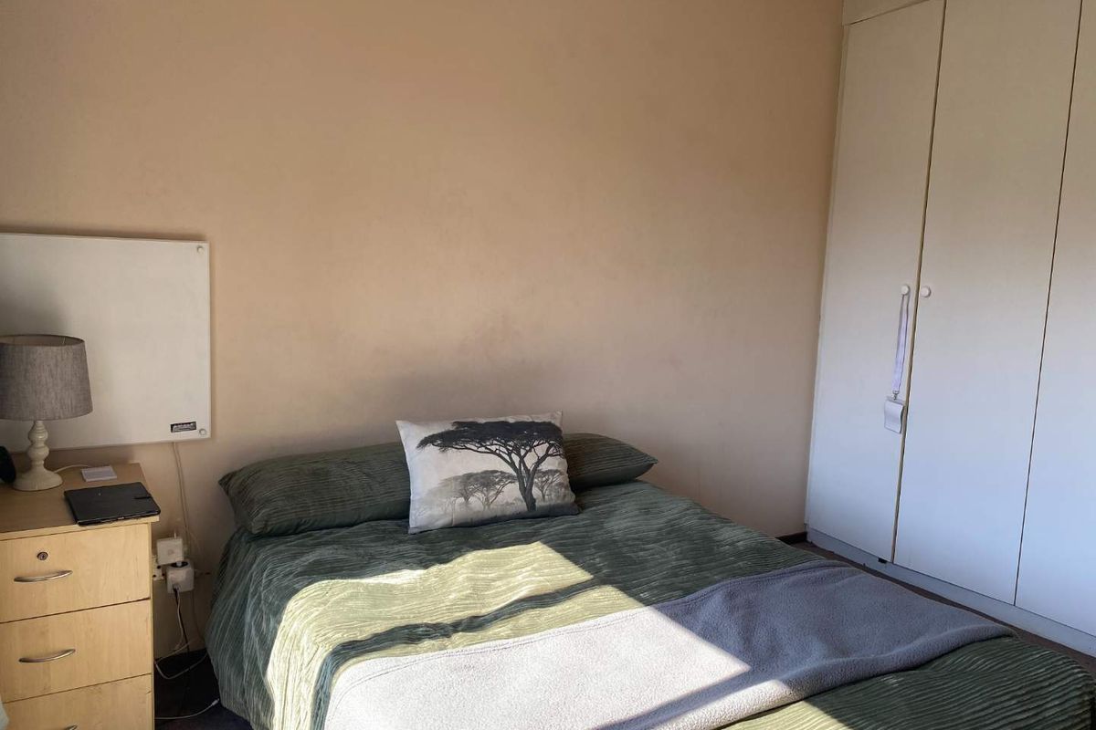 A functional bedroom featuring built-in wardrobes and a wall-mounted heater, providing a practical and comfortable living space.
