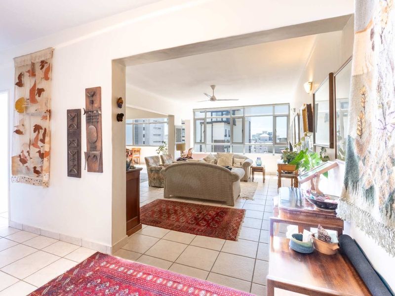 Spacious open-plan living area featuring tiled flooring, a ceiling fan, and large windows that provide ample natural light and urban views.