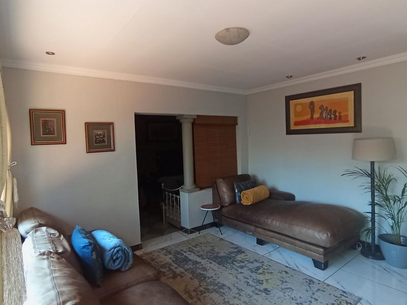 A comfortable living room featuring tiled flooring, recessed lighting, and decorative coving, providing a neutral base for interior design.