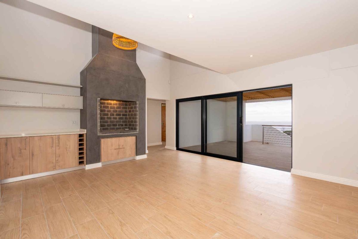 Spacious living area featuring a built-in fireplace, modern cabinetry, and large sliding glass doors opening onto a balcony with scenic views.