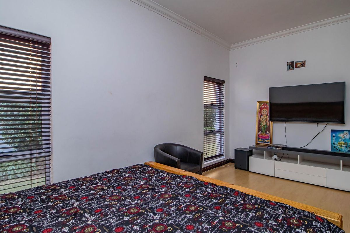 A bedroom featuring laminate flooring, coving, and venetian blinds on the windows.