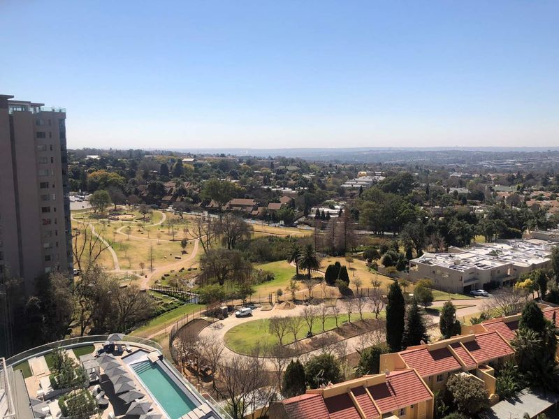 Elevated panoramic view overlooking a landscaped park, residential neighborhood, and a swimming pool area.