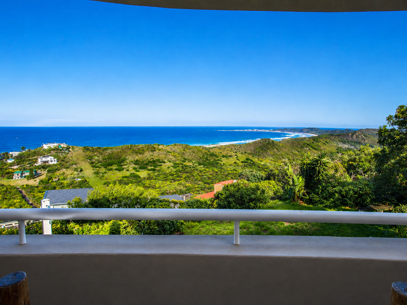A panoramic coastal view overlooking the ocean, rolling green hills, and surrounding residential landscape from an elevated balcony.