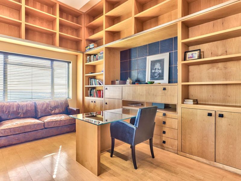 A dedicated home office featuring extensive built-in floor-to-ceiling wooden shelving, custom cabinetry, and hardwood flooring, providing ample storage and a professional workspace.