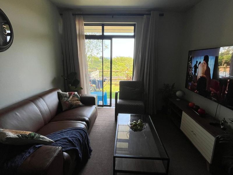 A comfortable living room featuring carpeted flooring and a sliding glass door that provides natural light and access to the outdoor area.