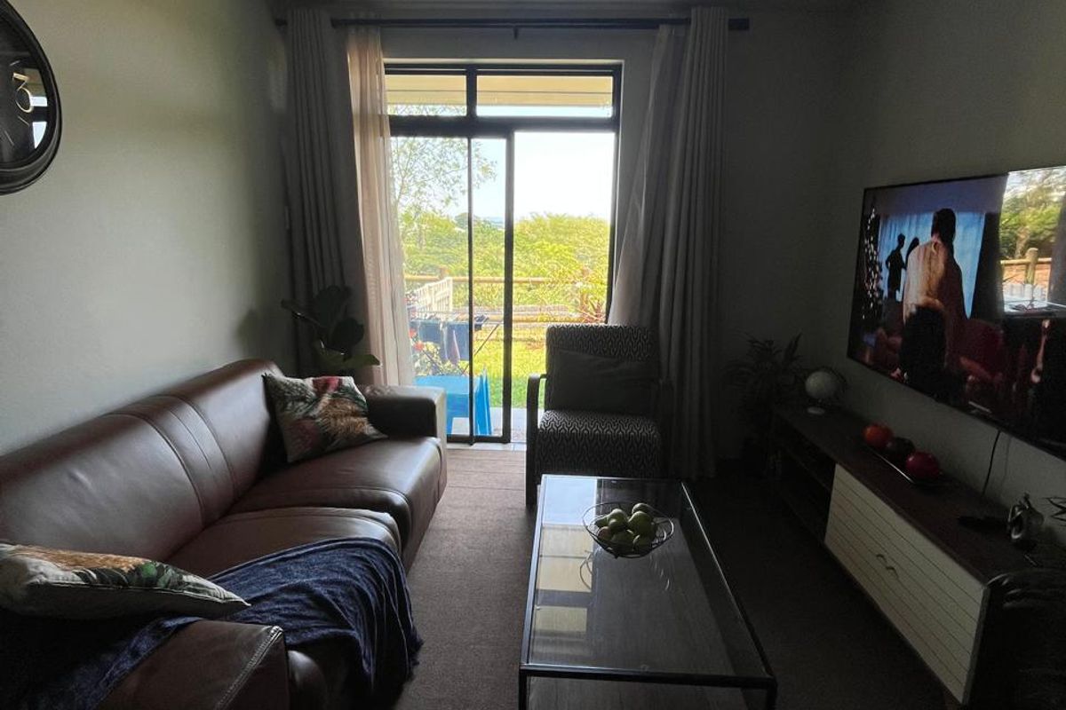 A comfortable living room featuring carpeted flooring and a sliding glass door that provides natural light and access to the outdoor area.