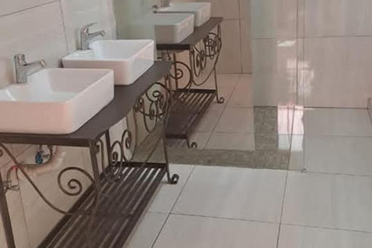 Modern bathroom featuring a double vanity with vessel sinks, large wall mirror, and a glass-enclosed shower area with floor-to-ceiling tiling.