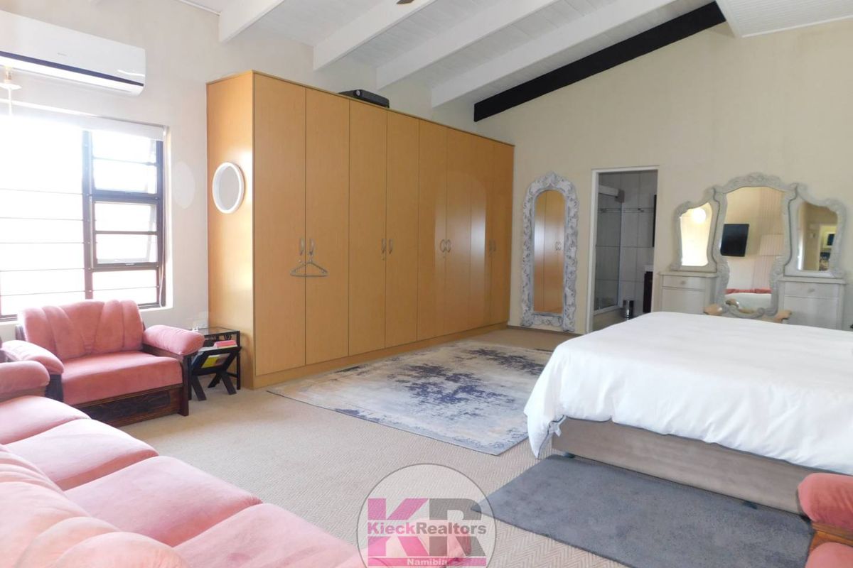 Spacious bedroom featuring high vaulted ceilings with exposed beams, built-in wooden cabinetry, and an en-suite bathroom access.