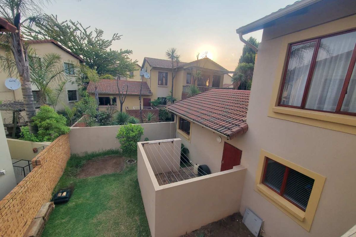 An elevated view of the rear townhouse garden featuring a small lawn, paved drying courtyard, and surrounding brick boundary walls.