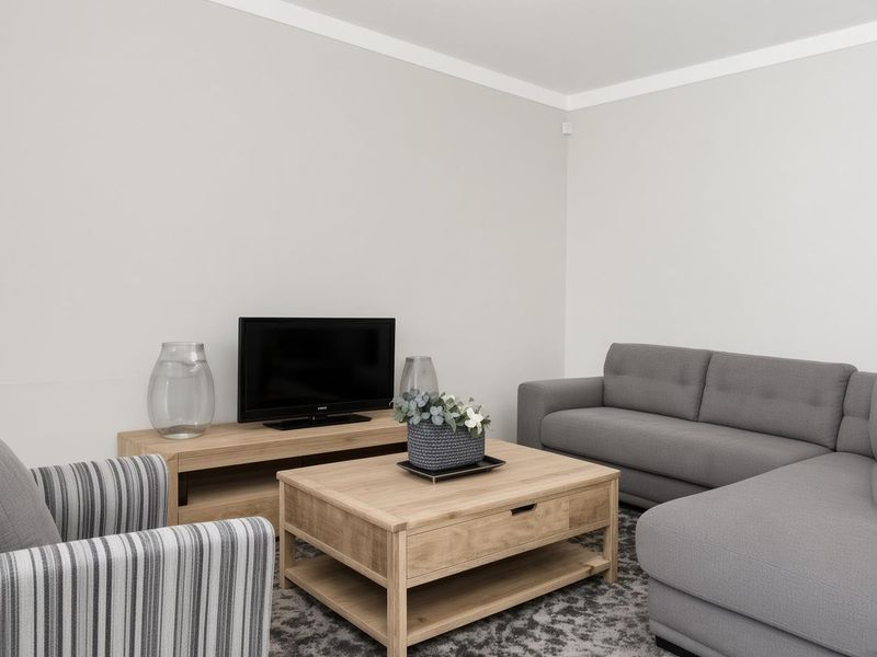 A well-maintained living room featuring neutral wall finishes, coving, and a security sensor, providing a clean and functional space.
