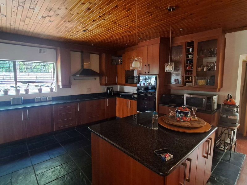 Spacious kitchen featuring timber ceilings, granite countertops, a central island, and built-in appliances with ample storage cabinetry.