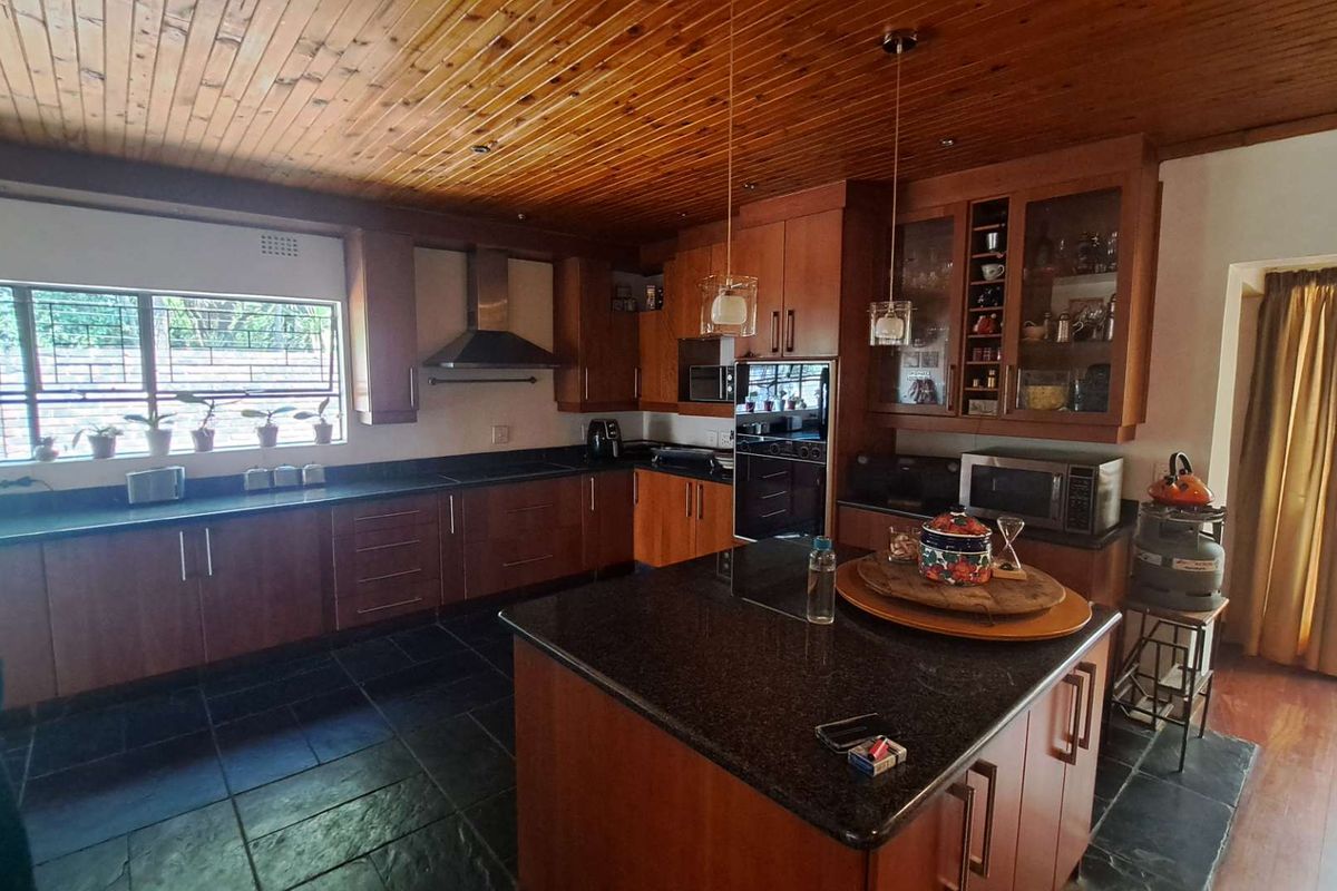 Spacious kitchen featuring timber ceilings, granite countertops, a central island, and built-in appliances with ample storage cabinetry.