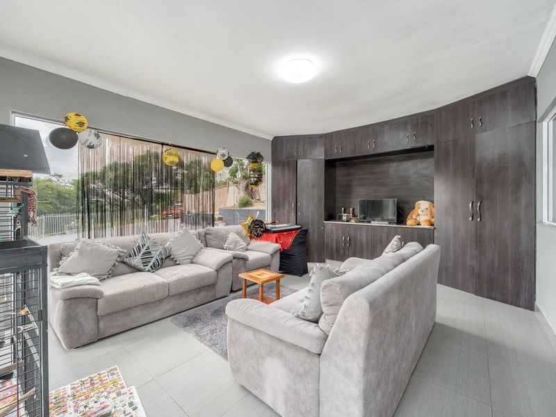 A living room featuring extensive dark wood built-in cabinetry, tiled flooring, and a large window providing natural light.