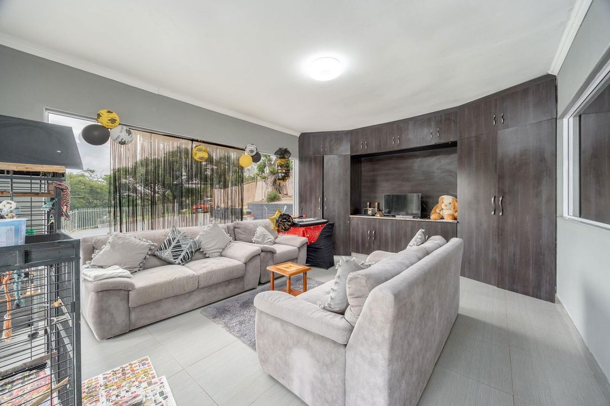 A living room featuring extensive dark wood built-in cabinetry, tiled flooring, and a large window providing natural light.