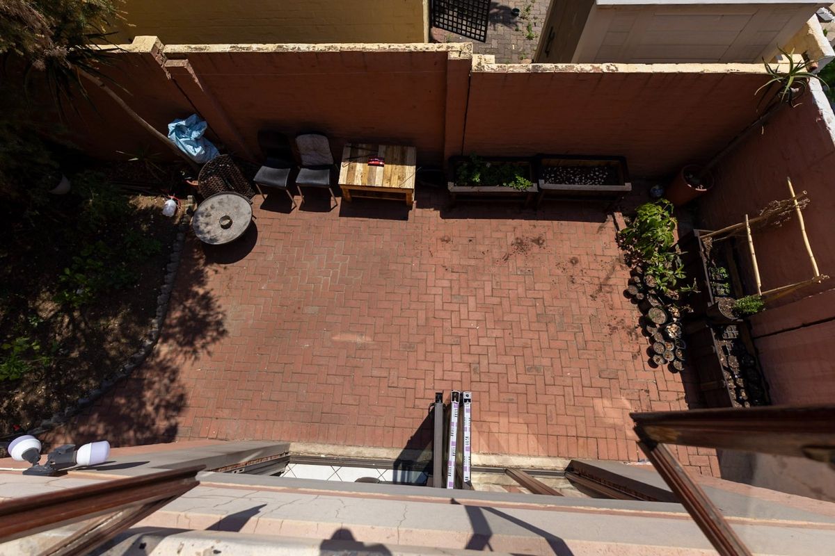 An elevated view of a private rear courtyard featuring brick paving and a perimeter boundary wall, offering a blank canvas for outdoor landscaping.