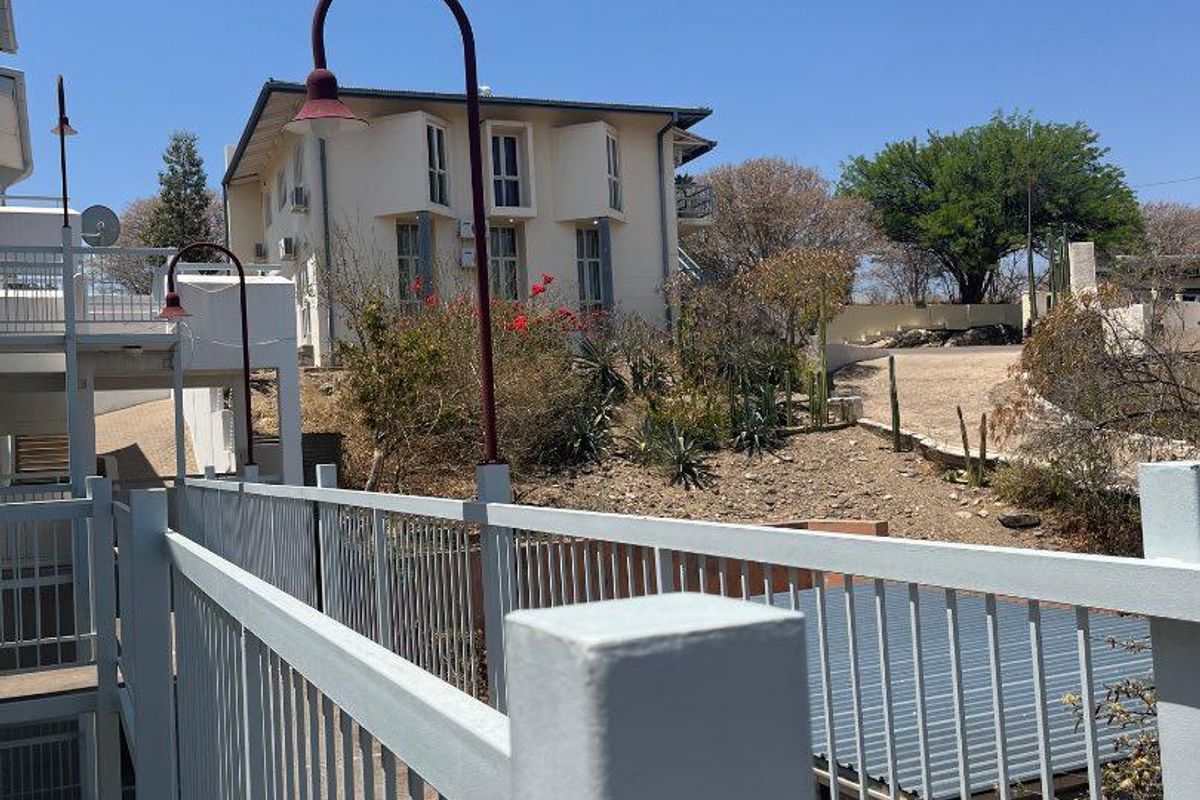 An elevated exterior walkway with metal railings overlooking the rear grounds and adjacent building structure.