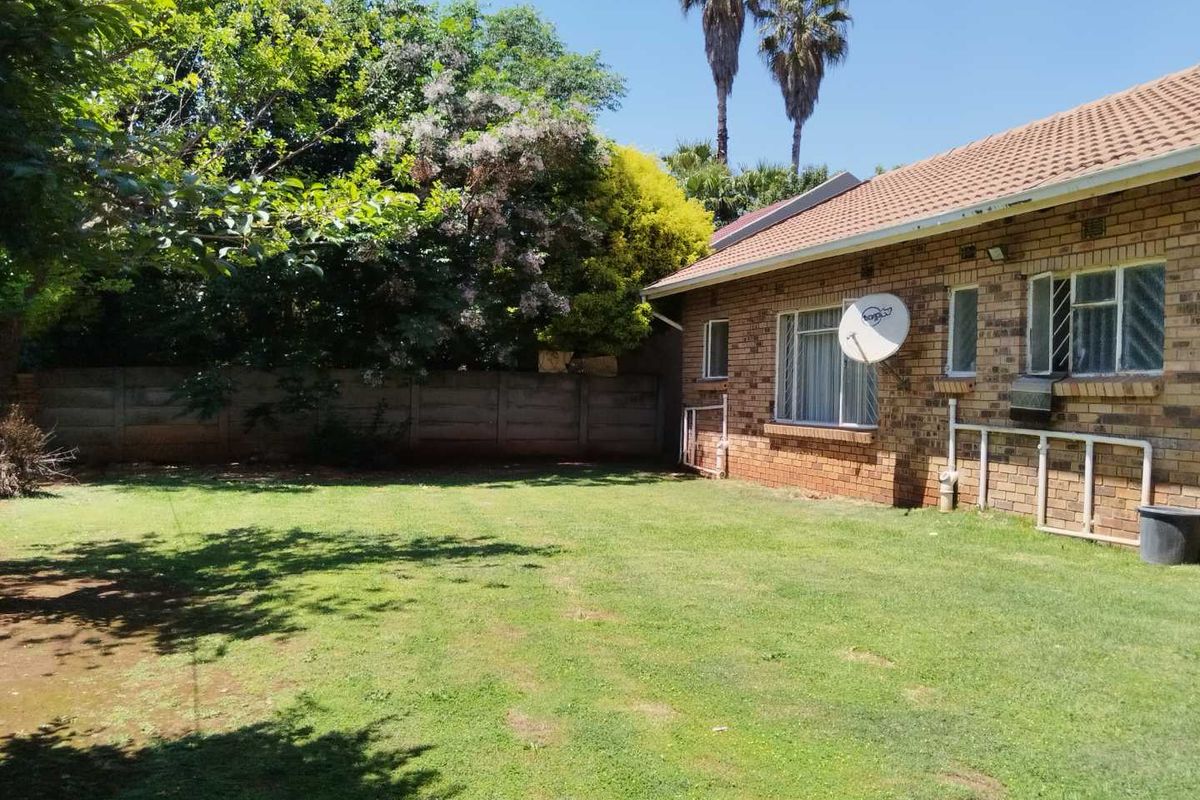 A view of the rear garden featuring a brick exterior, tiled roof, and precast concrete boundary wall.